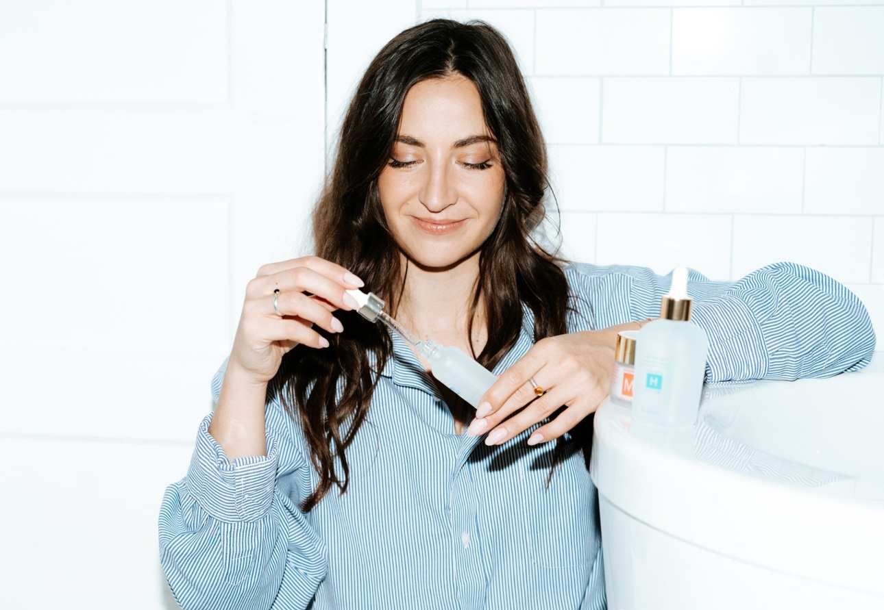 woman in bathroom taking product out of a bottle