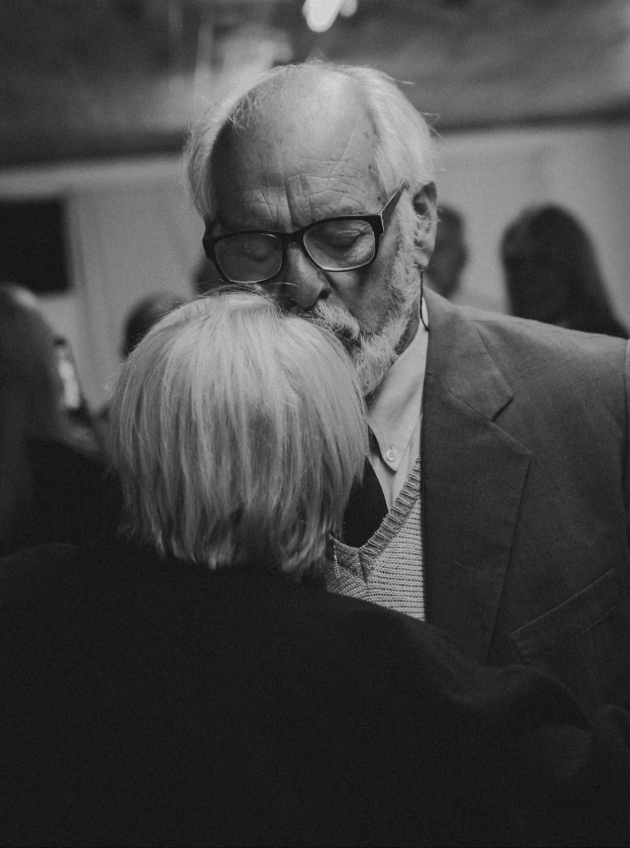 elderly man kissing wife's head