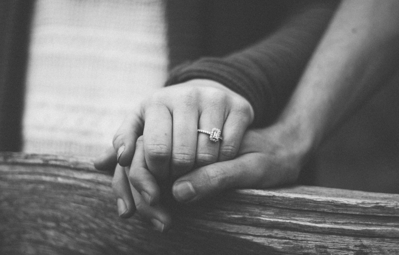 black and white image with a hand with an engagement ring on